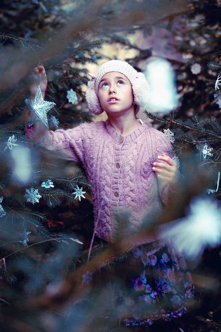 dítě s hvězdou při vánočním focení v ozdobeném lese