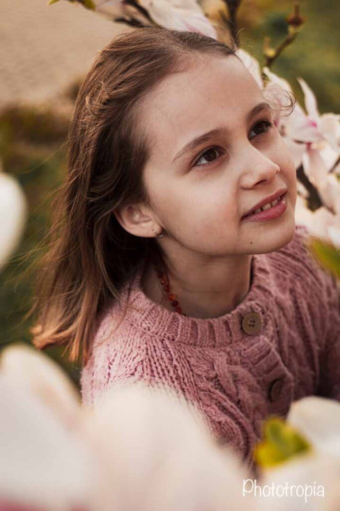 Dětský portrét uprostřed rozkvetlé magnolie.