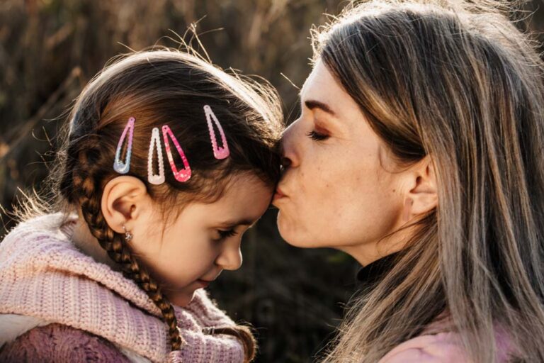 Maminka líbá malou dceru na čelo