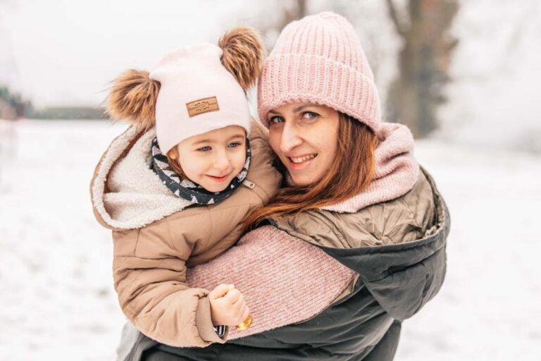 maminka s malou dcerou se objímají v zimě na sněhu